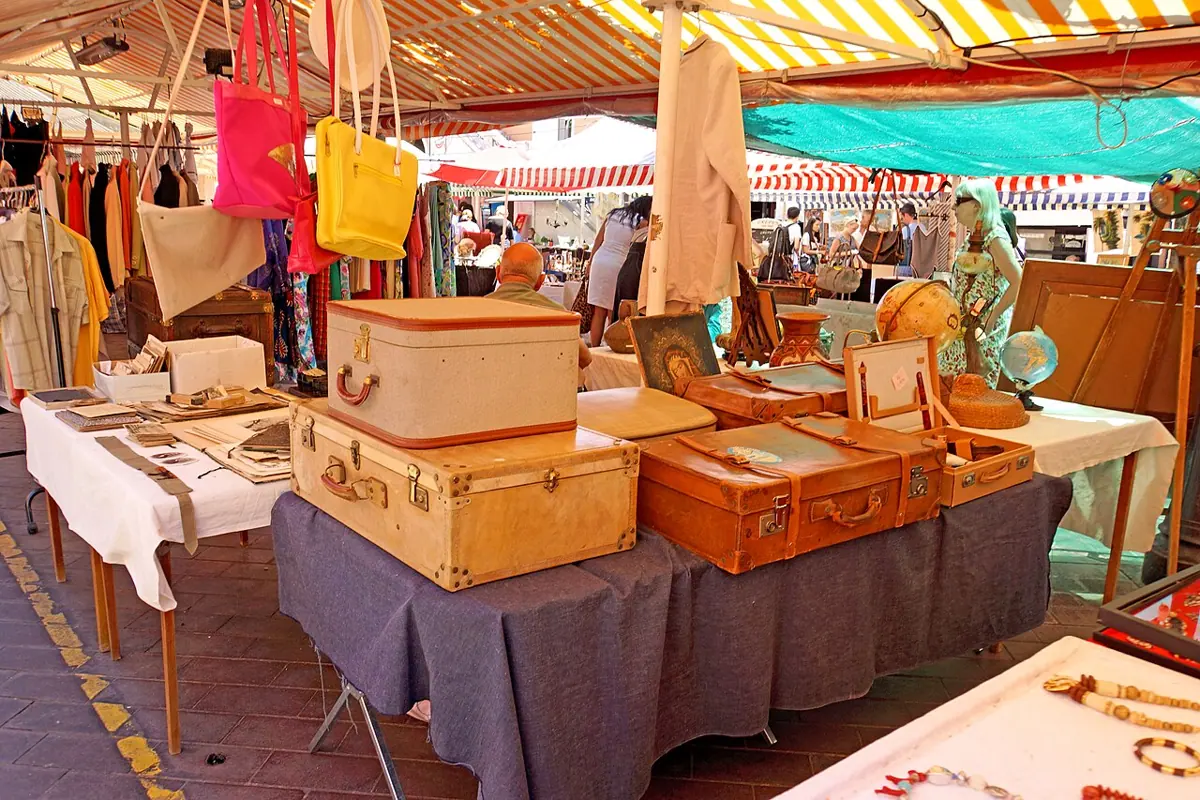 Antiquitäten und alte Reisekoffer an einem Marktstand auf dem Cours Saleya in Nizza.