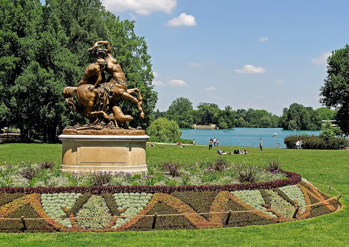 Blumenbeete und eine Skulpturengruppe vor dem See im Parc de la Tête d’Or in Lyon.