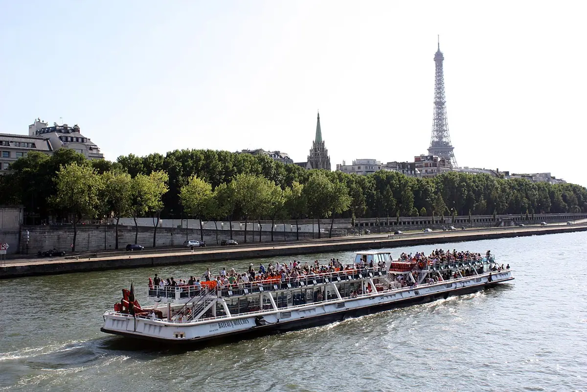 Ein Ausflugsboot auf der Seine mit dem Eiffelturm im Hintergrund.